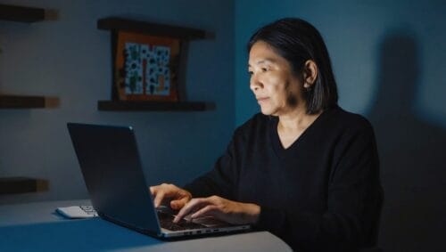 Online addiction treatment - A middle-aged person sitting in front of the laptop in a darkened room